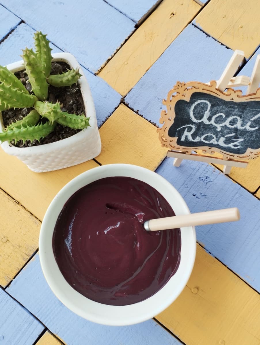 Tigela de açaí batido ao lado de uma placa escrita Açaí Raiz